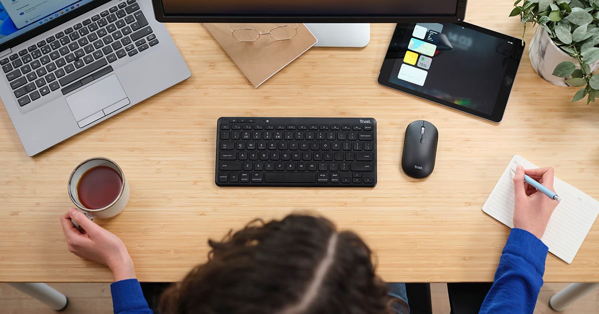 woman on desk with Trust keyboard and mouse
